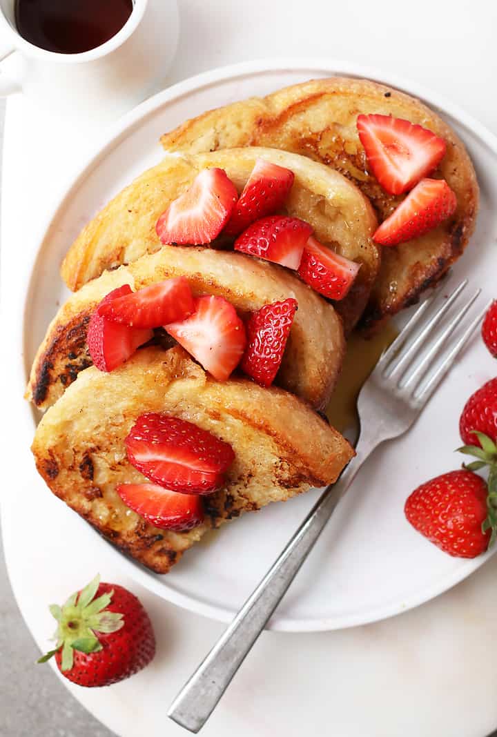 Classic Vegan French Toast with sliced strawberries and maple syrup.