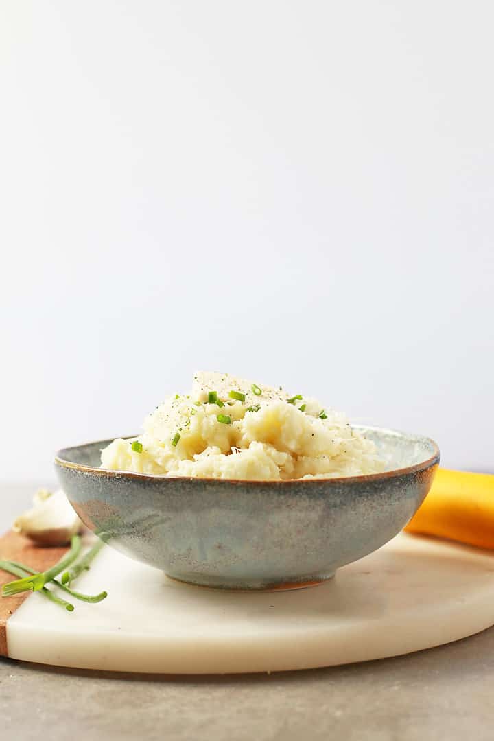 Cauliflower Mashed Potatoes in a blue bowl with chives and butter