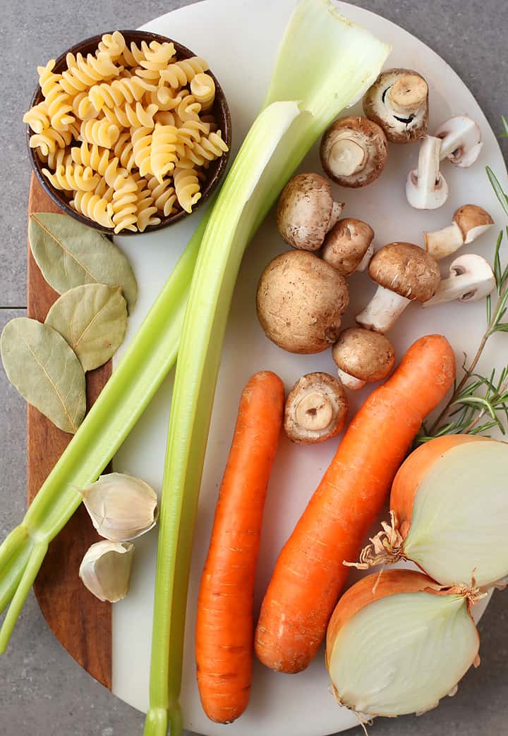 Carrots, onions, mushrooms, and celery on a cutting board