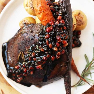 Finished recipe on a white plate with roasted carrots and potatoes