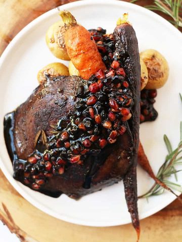 Finished recipe on a white plate with roasted carrots and potatoes