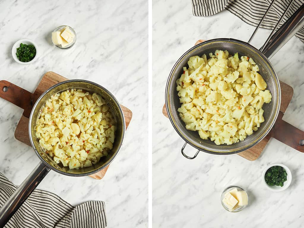 Boiled cauliflower and garlic cloves in a sauce pot on a cutting board. 