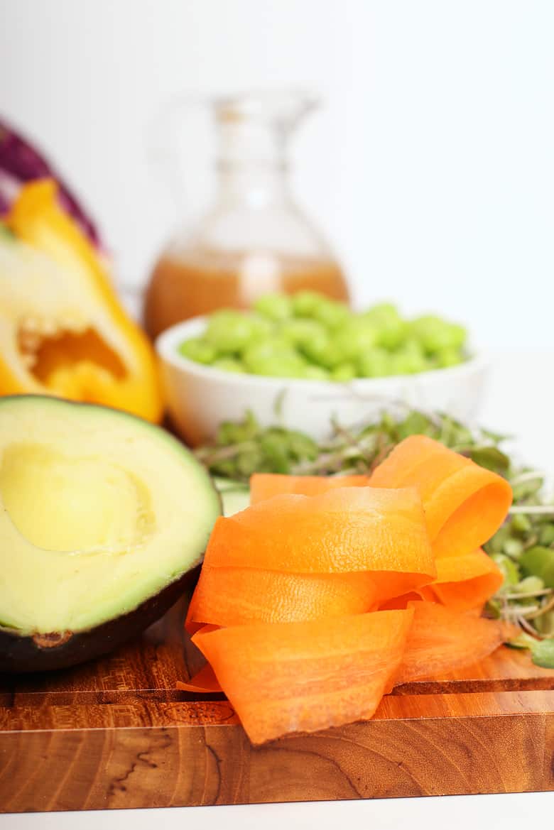 Carrots, avocado, and edamame on a cutting board