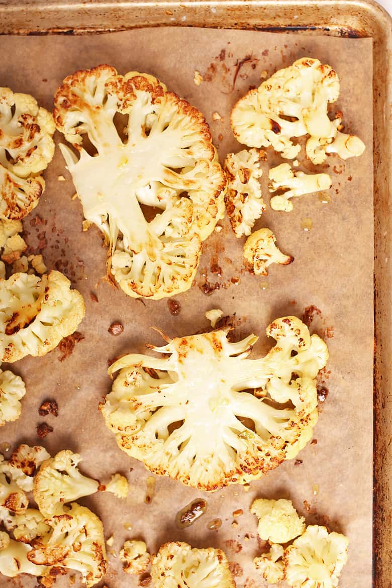 Cooked cauliflower steaks on a baking sheet