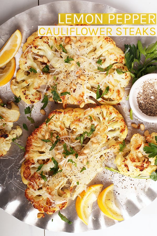 Impress all your friends with this vegan baked Lemon Pepper Cauliflower Steaks. A tender and creamy steak topped with fresh parsley, toasted pine nuts, and non-dairy parmesan cheese. Serve it with pasta or a giant salad for a delicious gluten-free and plant-based meal. #vegan #cauliflower
