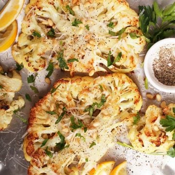 Two cauliflower steaks on silver platter