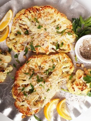 Two cauliflower steaks on silver platter