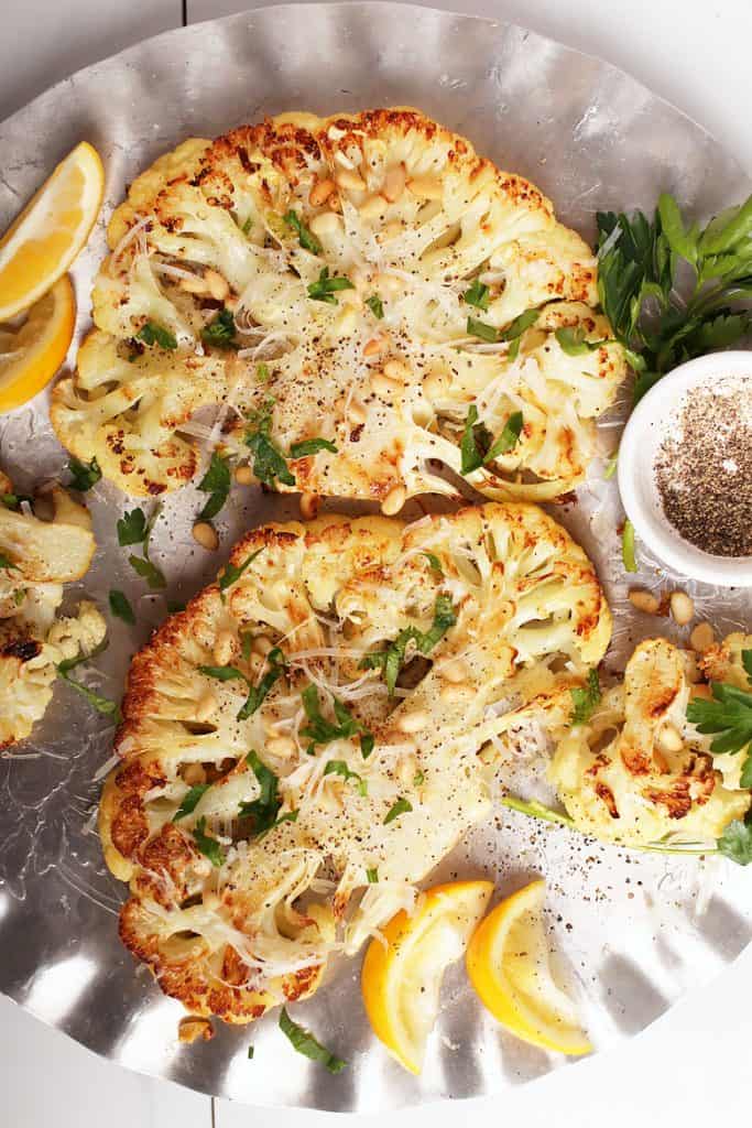 Two cauliflower steaks on silver platter