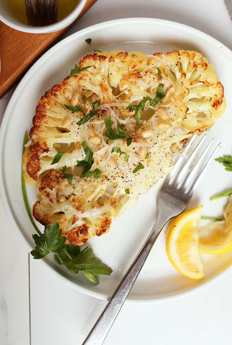 Finished recipe with fresh parsley and lemon wedges on a white plate. 