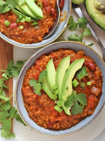 Two bowls of vegan chili with avocado and cilantro