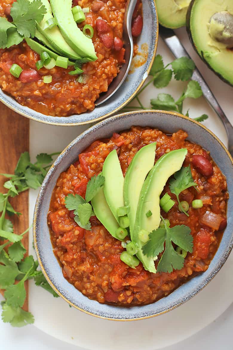 Two bowls of vegan chili with avocado and cilantro