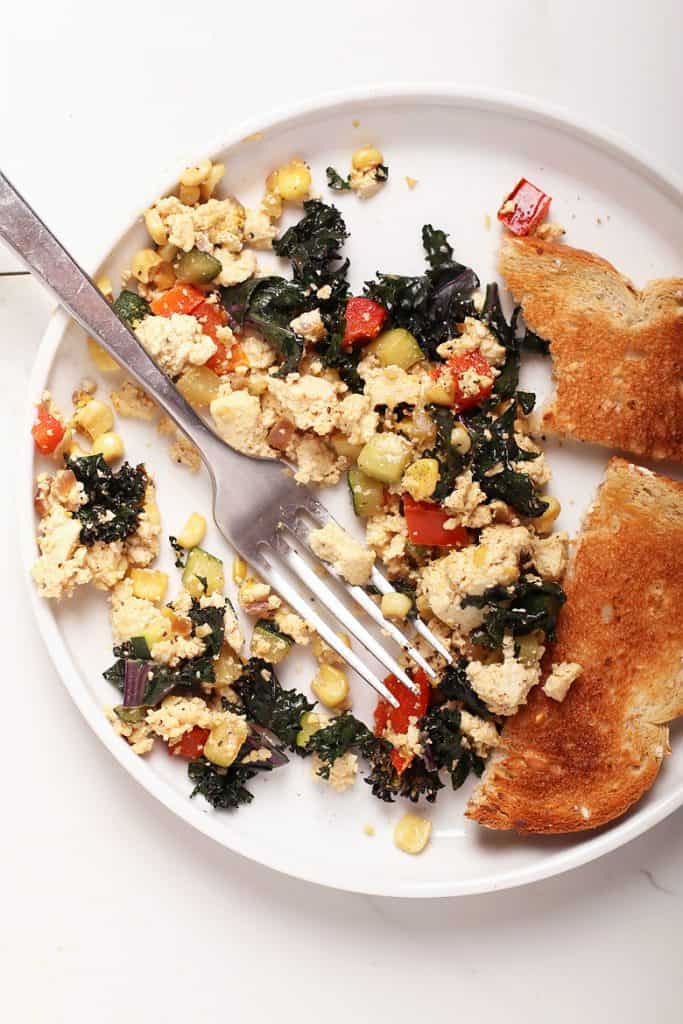 Tofu scramble on a white plate with a fork
