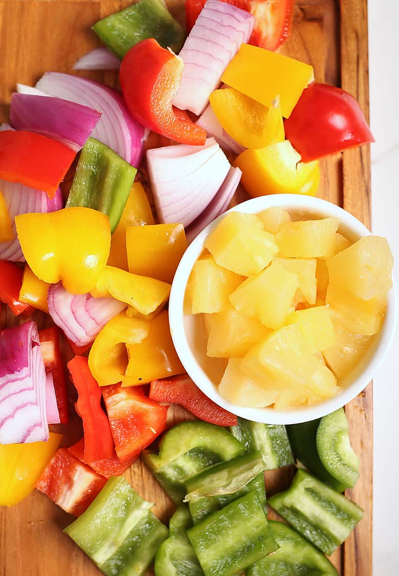 onions, bell peppers, and pineapple on a cutting board