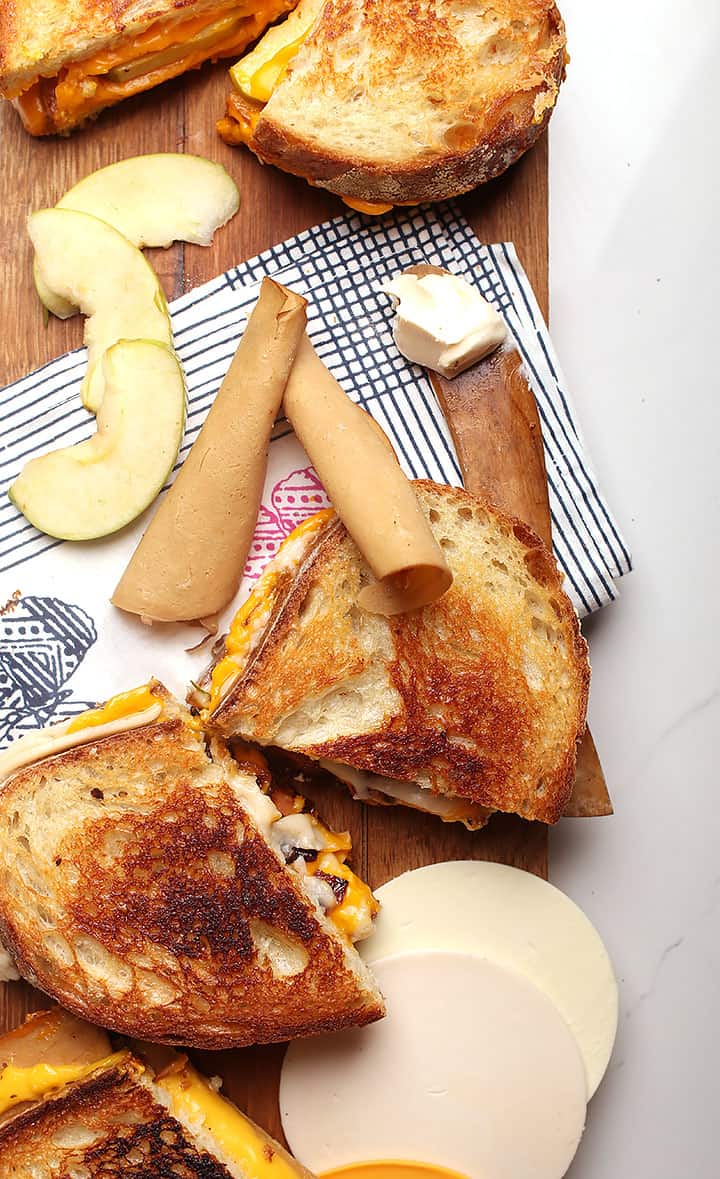 Finished sandwich on cutting board with apples and cheese