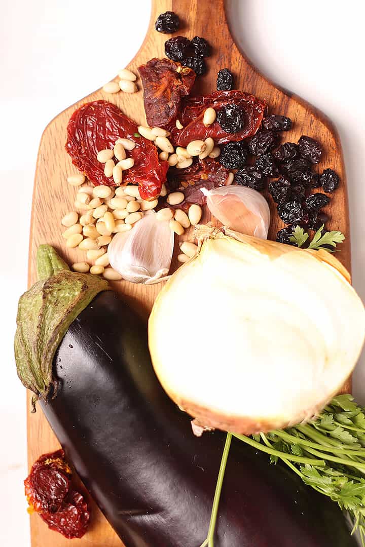 Eggplant, onions, garlic, and sun-dried tomatoes on cutting board