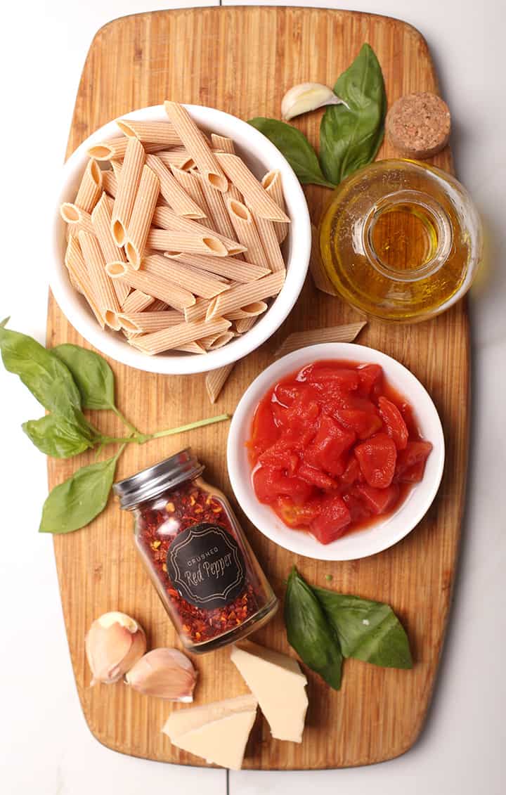 Pasta, tomatoes, garlic, and basil on cutting board