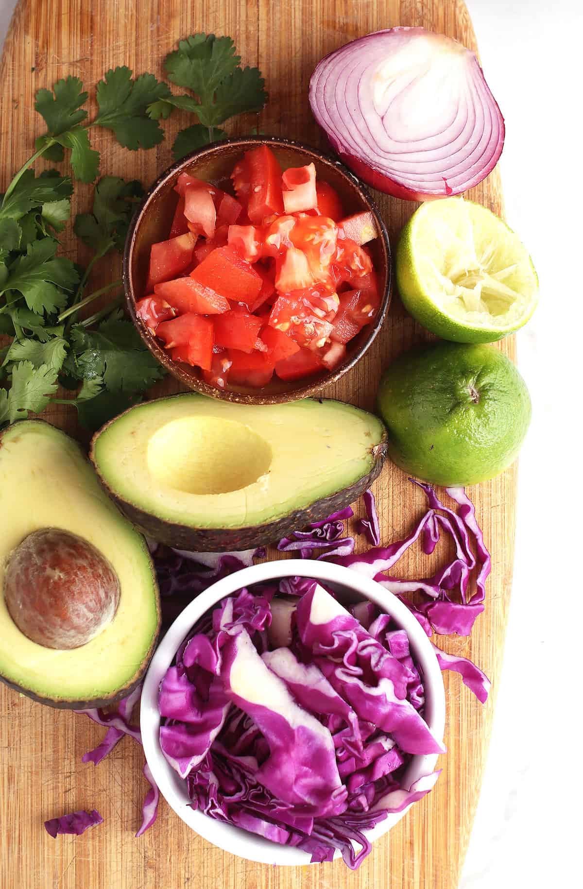 Avocado, tomato, cabbage, and cilantro on cutting board