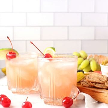 Two pink cocktails with lime and cherries