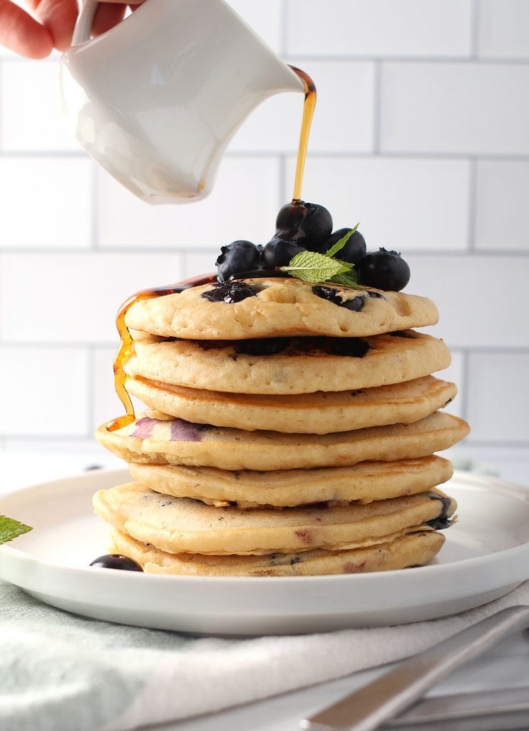 Stack of finished pancakes with fresh maple syrup