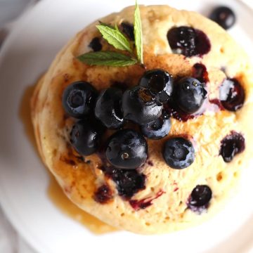Overhead shot of blueberry pancakes on a white plate