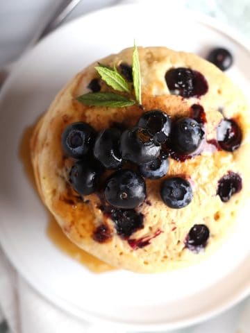 Overhead shot of blueberry pancakes on a white plate