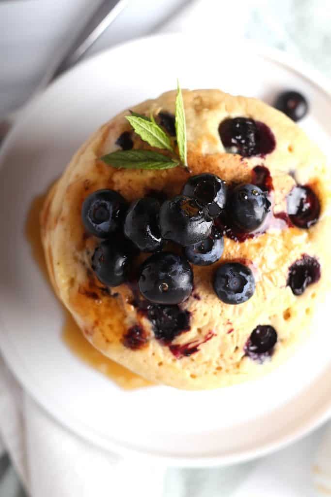 Overhead shot of blueberry pancakes on a white plate