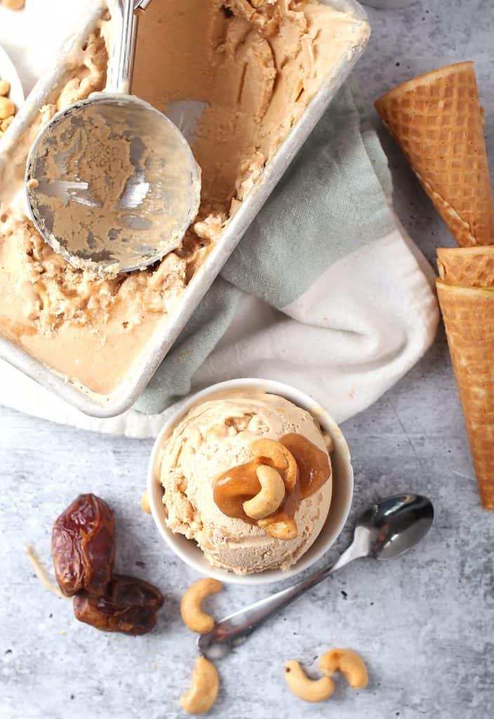 Finished ice cream in a white bowl next to cones