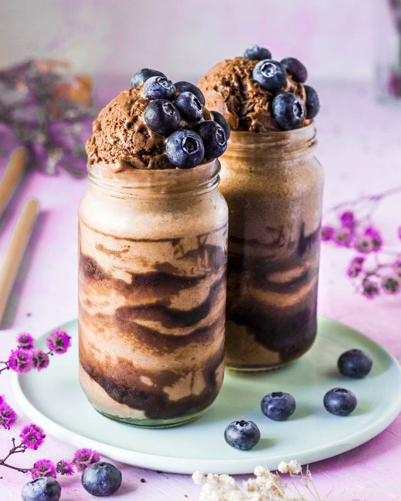 Two chocolate banana smoothies topped with blueberries