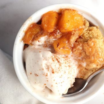 Finished cobbler in a white bowl with vanilla ice cream