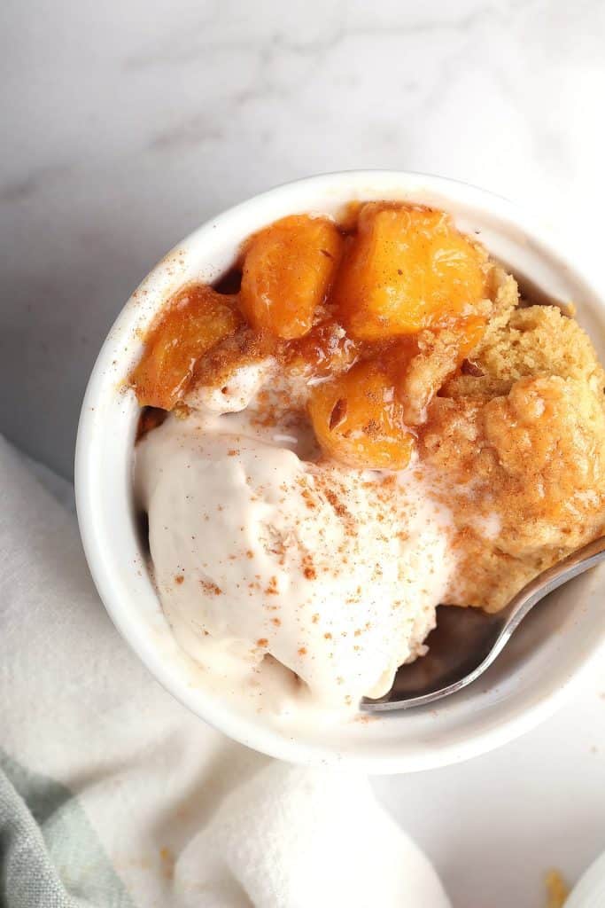 Finished cobbler in a white bowl with vanilla ice cream