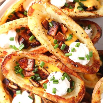 Finished potato skins stacked on a white plate