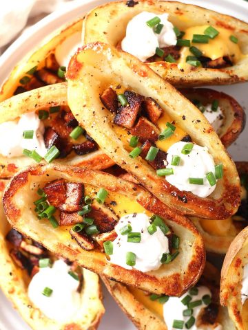 Finished potato skins stacked on a white plate