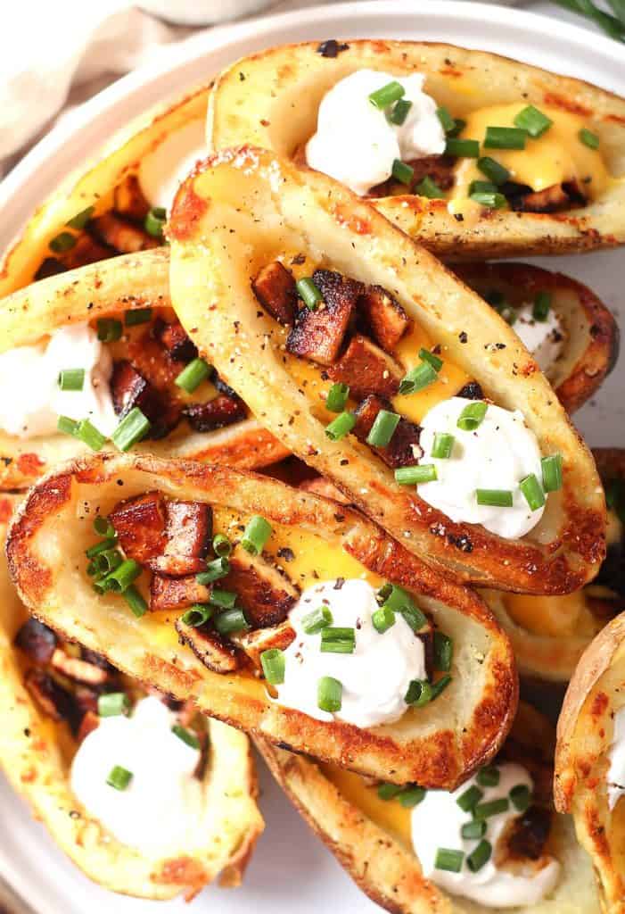 Finished potato skins stacked on a white plate