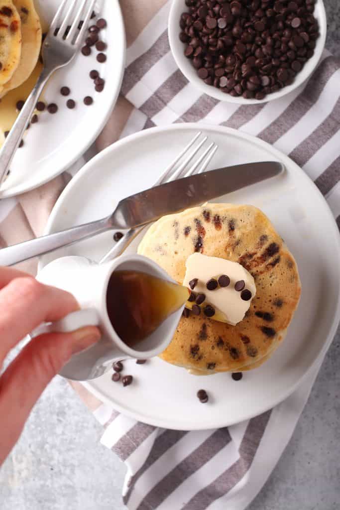 Syrup poured over a plate of chocolate chip pancakes