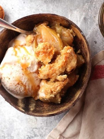 Finished apple cobbler in a brown bowl with ice cream