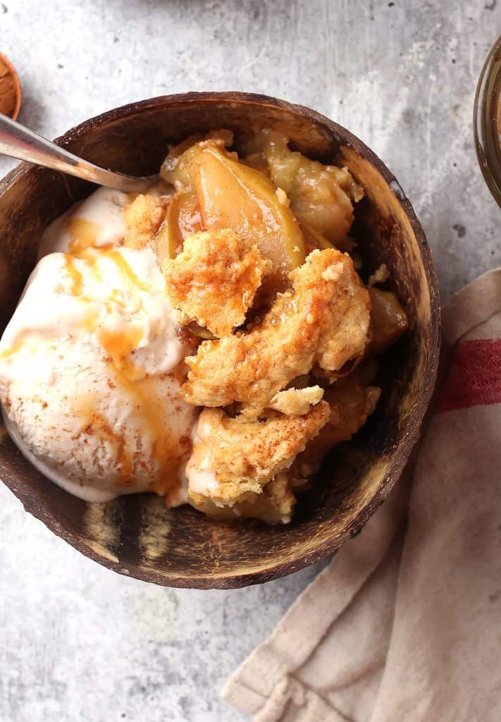 Finished apple cobbler in a brown bowl with ice cream