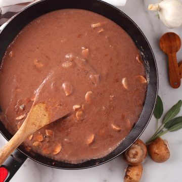Finished gravy in a skillet with a wooden spoon