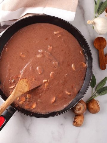 Finished gravy in a skillet with a wooden spoon