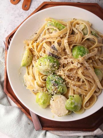 Finished Alfredo pasta in a white plate with a fork