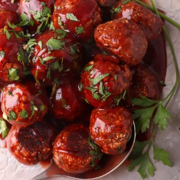 Finished vegan meatballs on a silver platter with a serving spoon