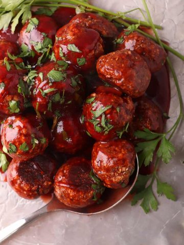 Finished vegan meatballs on a silver platter with a serving spoon