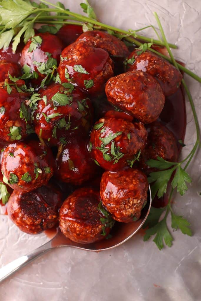 Finished vegan meatballs on a silver platter with a serving spoon