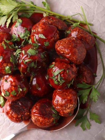 Finished vegan meatballs on a silver platter with a serving spoon