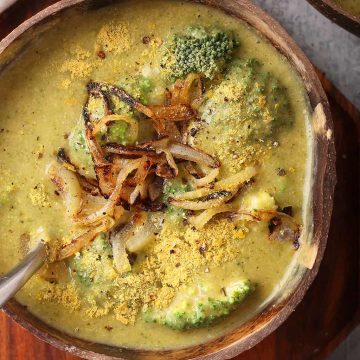 Bowl of homemade broccoli cheese soup on a wooden platter