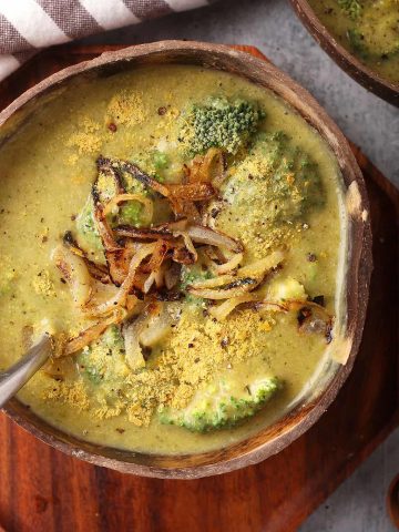 Bowl of homemade broccoli cheese soup on a wooden platter