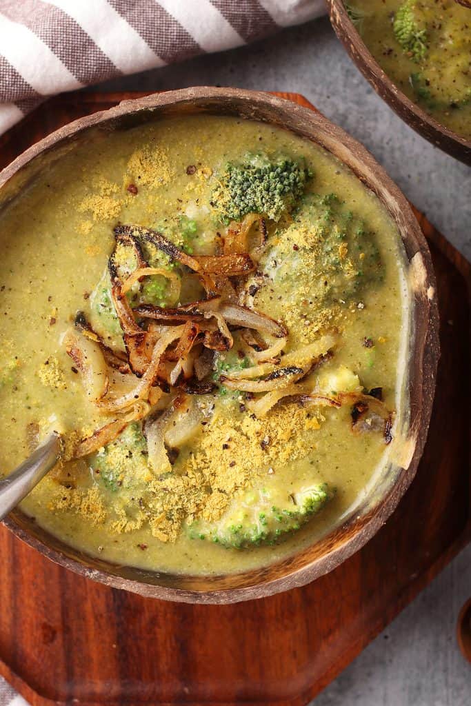 Bowl of homemade broccoli cheese soup on a wooden platter