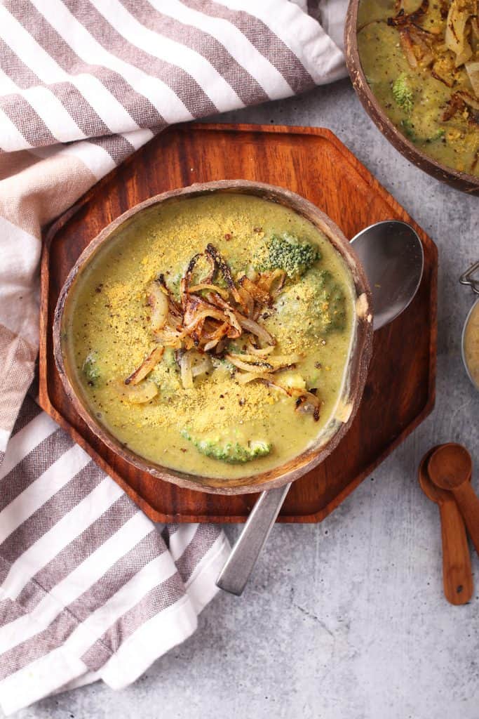 Bowl of homemade broccoli cheese soup on a wooden platter