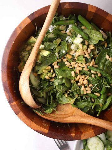 Finished salad in a wooden salad bowl with tongs