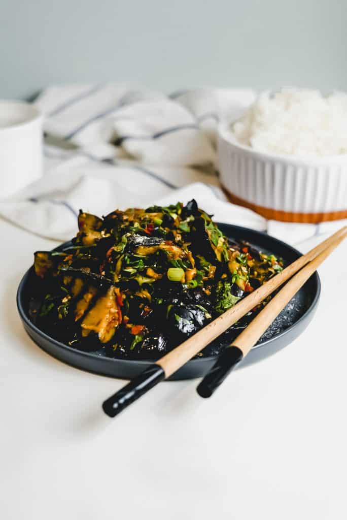 Grilled Chinese Eggplant on a black plate with chopsticks