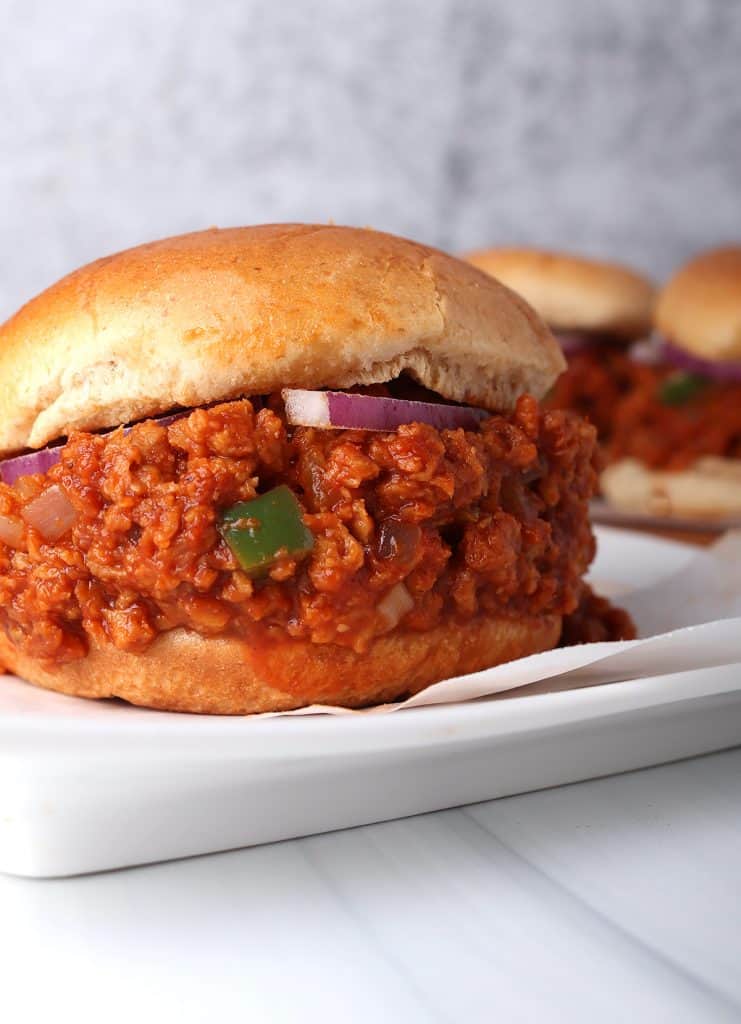 close up shot of homemade vegan sloppy joe on a hamburger bun on a white plate